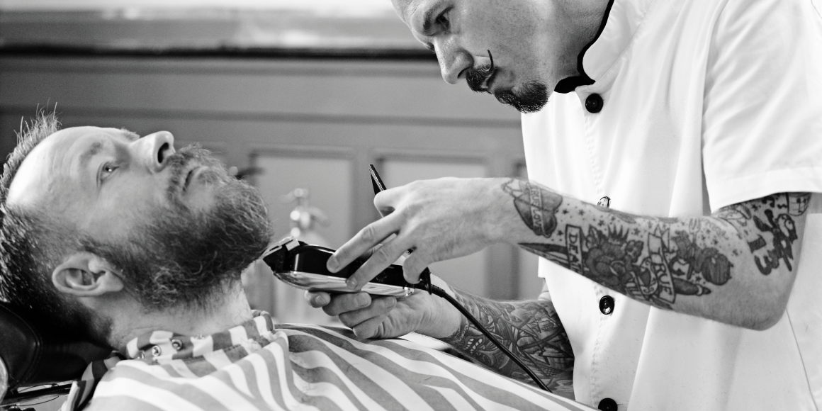 barber cutting beard hair with trimmer